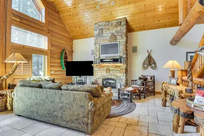 a living room with a couch and a stone fireplace at 2 Cabins Group and Family Getaway in Arnold! in Arnold