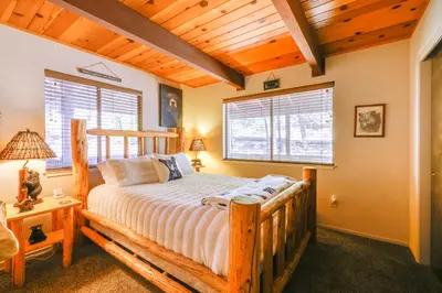 a bedroom with a wooden bed in a room at Furnished Deck High Sierra Cabin in Twain Harte! in Twain Harte