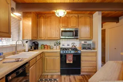 a kitchen with wooden cabinets and a black stove top oven at Furnished Deck High Sierra Cabin in Twain Harte! in Twain Harte