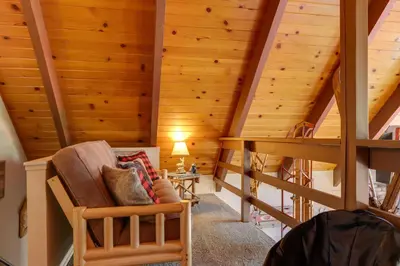 an attic room with wooden ceilings and a chair at Furnished Deck High Sierra Cabin in Twain Harte! in Twain Harte