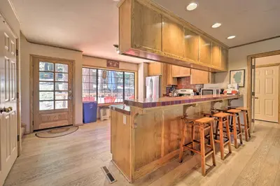 a kitchen with wooden cabinets and a bar with stools at Wraparound Deck and Pool Access Truckee Cabin in Truckee