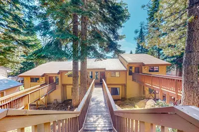a house in the woods with a wooden walkway at Huntington Lake Condo #102 in Lakeshore