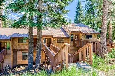 a log home with a deck in the woods at Huntington Lake Condo #102 in Lakeshore