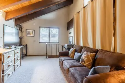 a living room with a brown couch and a television at Mammoth Pines #7 Newly updated 2 Bedroom plus Loft, 3 Full Bathrooms, Sleeps 8 people in Mammoth Lakes