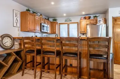 a kitchen with wooden cabinets and a bar with stools at Mammoth Pines #7 Newly updated 2 Bedroom plus Loft, 3 Full Bathrooms, Sleeps 8 people in Mammoth Lakes