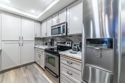 a kitchen with white cabinets and a stainless steel refrigerator at Mountainback 100 in Mammoth Lakes