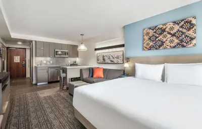 a hotel room with a large bed and a kitchen at Hyatt House Sacramento-Midtown in Sacramento