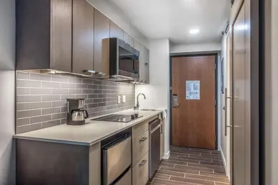a kitchen with wooden cabinets and a sink and a door at Hyatt House Sacramento-Midtown in Sacramento