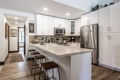 a kitchen with white cabinets and a stainless steel refrigerator at Horizons IV #156 New Luxurious Listing! Fully Remodeled 2 Bedroom Plus Loft 3 Full Bathroom Sleeps 8 in Mammoth Lakes