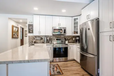 a kitchen with white cabinets and a stainless steel refrigerator at Horizons IV #156 New Luxurious Listing! Fully Remodeled 2 Bedroom Plus Loft 3 Full Bathroom Sleeps 8 in Mammoth Lakes