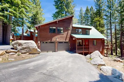 a wooden house with a garage in the woods at Falcon Point Pines in Truckee