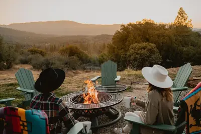 two people sitting around a fire pit at Scenic View Timber Lodge HotTub by Casa Oso in Mariposa
