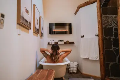 a woman sitting in a bath tub in a bathroom at Scenic View Timber Lodge HotTub by Casa Oso in Mariposa