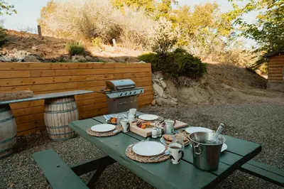 a picnic table with plates of food and a grill at Scenic View Timber Lodge HotTub by Casa Oso in Mariposa