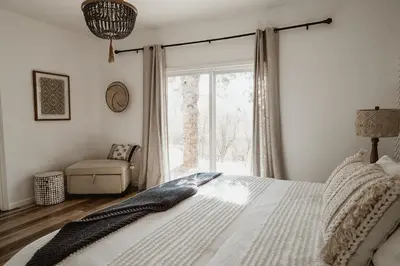 a bedroom with a bed and a chair and a window at Sunset Glow Hidden Meadow BBQ HotTub by Casa Oso in Oakhurst