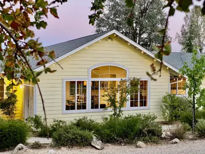 a house with yellow siding and a window at Sunset Glow Hidden Meadow BBQ HotTub by Casa Oso in Oakhurst