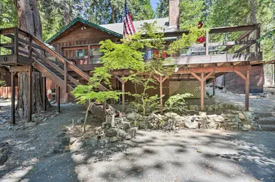 a log cabin with a balcony and an american flag at Comfortable Mi-Wuk Village Cabin Hike and Ski! in Mi-Wuk Village