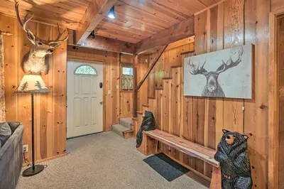 a living room with wooden walls and a hallway with a door at Comfortable Mi-Wuk Village Cabin Hike and Ski! in Mi-Wuk Village