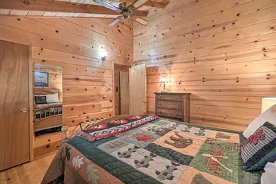 a bedroom with a bed in a room with wooden walls at Comfortable Mi-Wuk Village Cabin Hike and Ski! in Mi-Wuk Village