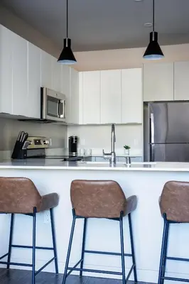 a kitchen with white cabinets and a counter with two bar stools at Kasa Archive Reno-Tahoe in Reno