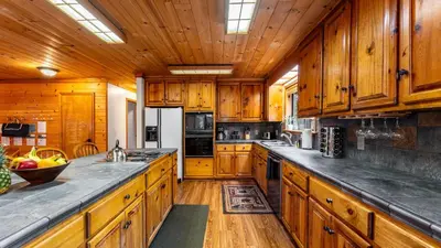 a large kitchen with wooden cabinets and wooden floors at Whiskey Springs by AvantStay Classic Cabin Near Tahoe Donner Ski Area in Truckee