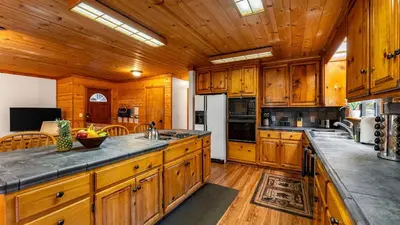 a kitchen with wooden cabinets and a large counter top at Whiskey Springs by AvantStay Classic Cabin Near Tahoe Donner Ski Area in Truckee