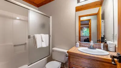 a bathroom with a sink and a toilet and a mirror at Whiskey Springs by AvantStay Classic Cabin Near Tahoe Donner Ski Area in Truckee