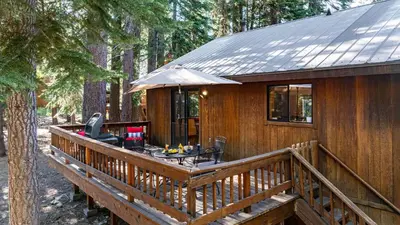 a wooden cabin with a deck with an umbrella at Whiskey Springs by AvantStay Classic Cabin Near Tahoe Donner Ski Area in Truckee