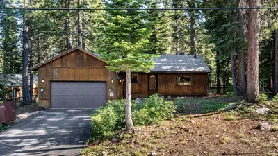 a house with a garage in the woods at Whiskey Springs by AvantStay Classic Cabin Near Tahoe Donner Ski Area in Truckee