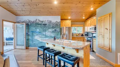 a kitchen with a sink and a counter with stools at Golden Summit by AvantStay Stunning Secluded Cabin w Access to Tahoe Donner in Truckee