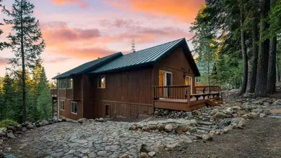 a log cabin in the woods with a stone walkway at Golden Summit by AvantStay Stunning Secluded Cabin w Access to Tahoe Donner in Truckee