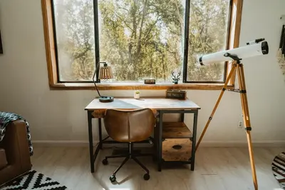 a camera on a tripod next to a desk in front of a window at Romantic Forest Lovers Nest by Casa Oso in Mariposa
