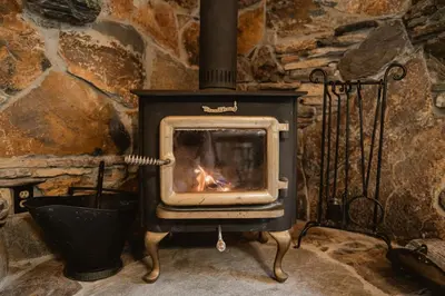 a stove with a fire in a stone wall at Romantic Forest Lovers Nest by Casa Oso in Mariposa