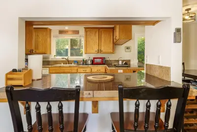 a kitchen with a large island with chairs in it at Acorn House - Charming house in green heaven with pool table with lovely backyard in Oakhurst