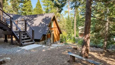 a cabin in the woods with a staircase and trees at Ember by AvantStay Majestic Entertainers Home w Pine Tree Views Close to Meeks Bay in Tahoma Meadows