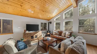 a living room with couches and a flat screen tv at Moosetrack by AvantStay Cozy Cabin w Hot Tub In The Heart of Tahoe Donner in Truckee