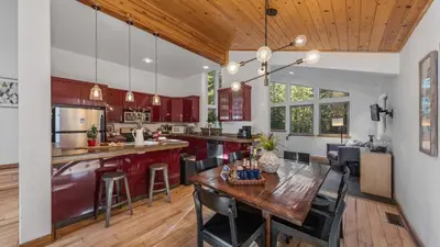 a kitchen with red cabinets and a wooden table at Moosetrack by AvantStay Cozy Cabin w Hot Tub In The Heart of Tahoe Donner in Truckee