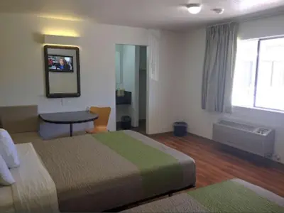 a hotel room with a bed and a table and a window at American Inn in Hawthorne