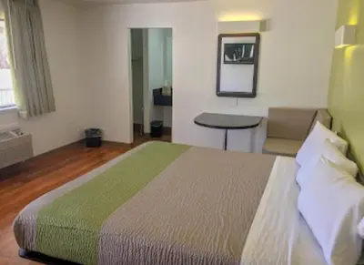 a bedroom with a bed and a table and a mirror at American Inn in Hawthorne