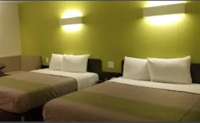 a hotel room with two beds and two lights on the wall at American Inn in Hawthorne