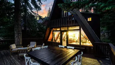 a house with a wooden table and chairs on a deck at Horizon by AvantStay Stunning A-frame Cabin w Hot Tub Billiards Lake Views in Tahoe City