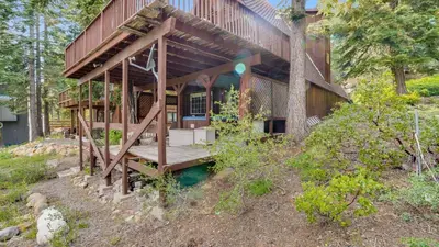 a house with a wooden porch in the woods at Horizon by AvantStay Stunning A-frame Cabin w Hot Tub Billiards Lake Views in Tahoe City