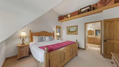 a bedroom with a large wooden bed and a bathroom at Ellis Peak by AvantStay Beautiful McKinney Cabin w Filtered Lake Views in Homewood