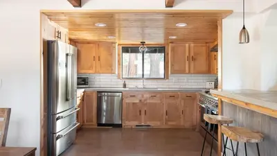 a kitchen with wooden cabinets and a stainless steel refrigerator at Timberline by AvantStay Stunning Chalet Cabin w Hot Tub Pool Table Home Theater in Tahoe Vista