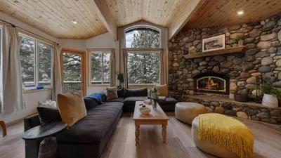 a living room with a couch and a stone wall at Sparrow by AvantStay Modern Mountain Retreat w Hot Tub Pool Table Games in Truckee