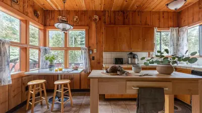 a kitchen with wooden cabinets and a table and stools at Sunnyside by AvantStay Charming Lake Tahoe Chalet on Tahoes West Shore in Tahoe City