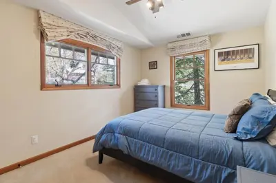 a bedroom with a blue bed and two windows at Better at the Lake Home with Private Dock in Groveland
