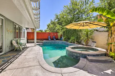 a swimming pool with an umbrella next to a house at Spacious Folsom Getaway with Pool and Hot Tub! in Folsom