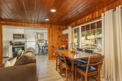 a kitchen and living room with a table and a couch at Acorn Cabin - Charming Place, Your getaway to Yosemite, Bass Lake in Oakhurst