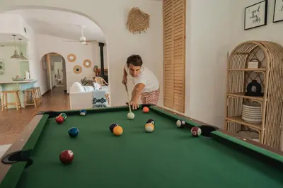a man playing pool in a living room at Boho chic oasis by Casa Oso with pool, spa and views in Ahwahnee
